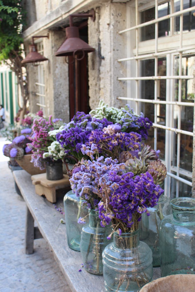 A vibrant arrangement of purple and pink flowers in glass vases, adorning a rustic outdoor setting.