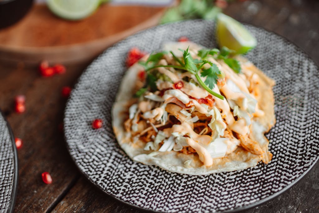 Close-up of a tasty chicken taco topped with cilantro and lime on a rustic plate.