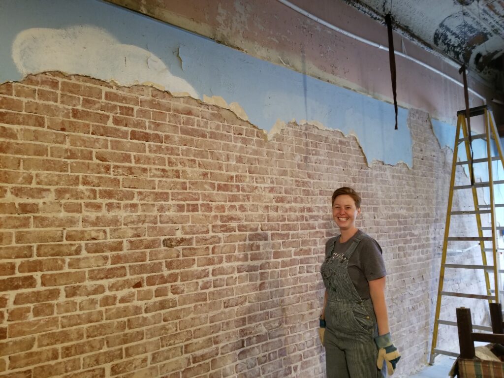 Woman standing by an exposed brick wall