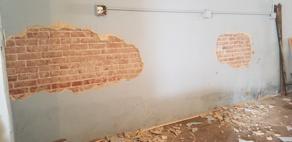 Small portions of exposed brick showing on plaster wall