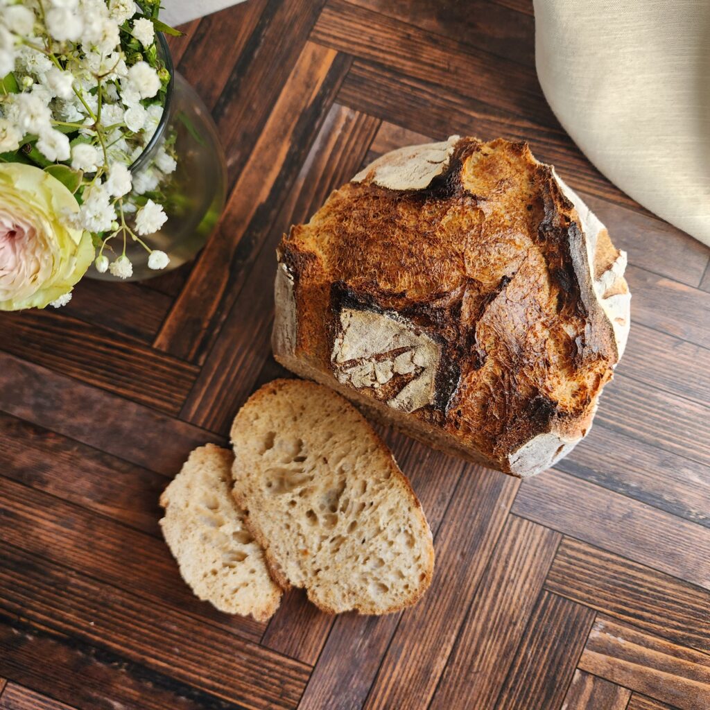 Made from scratch sourdough bread that is sliced next to a bouquet of flowers