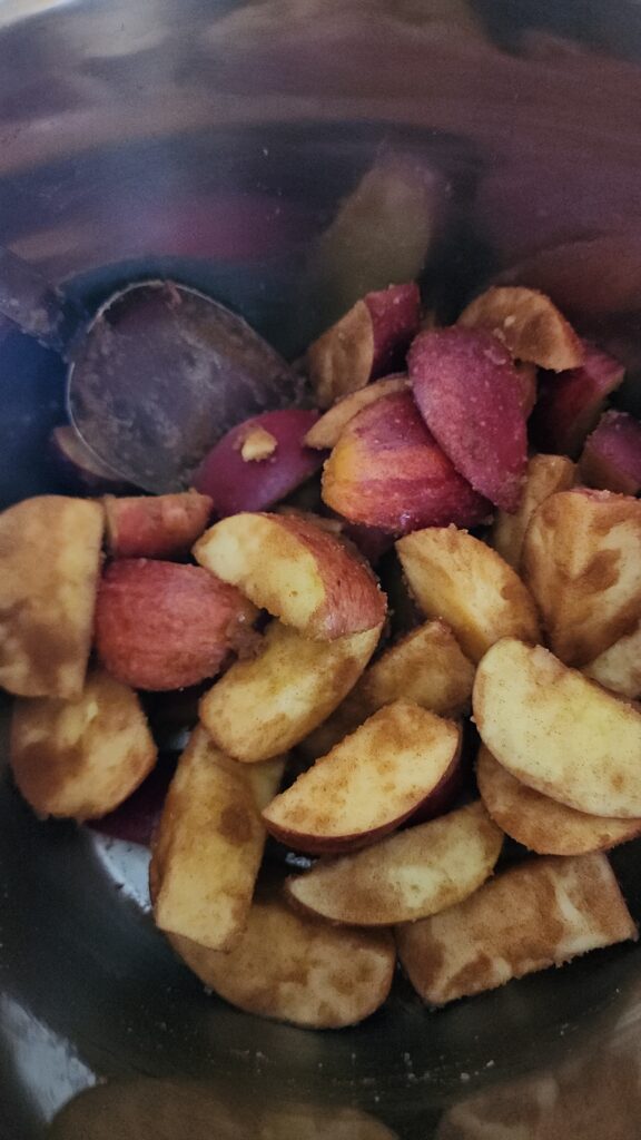 Sliced apples in bowl covered in sugar and spices