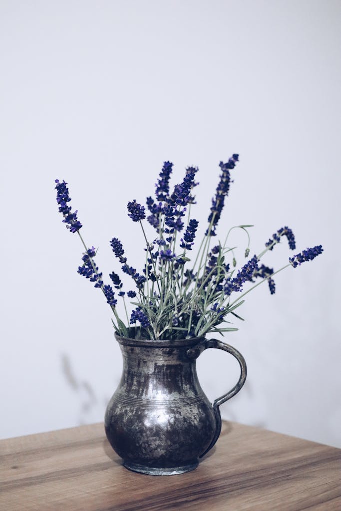 A charming display of lavender sprigs in a vintage metal vase on a wooden table.