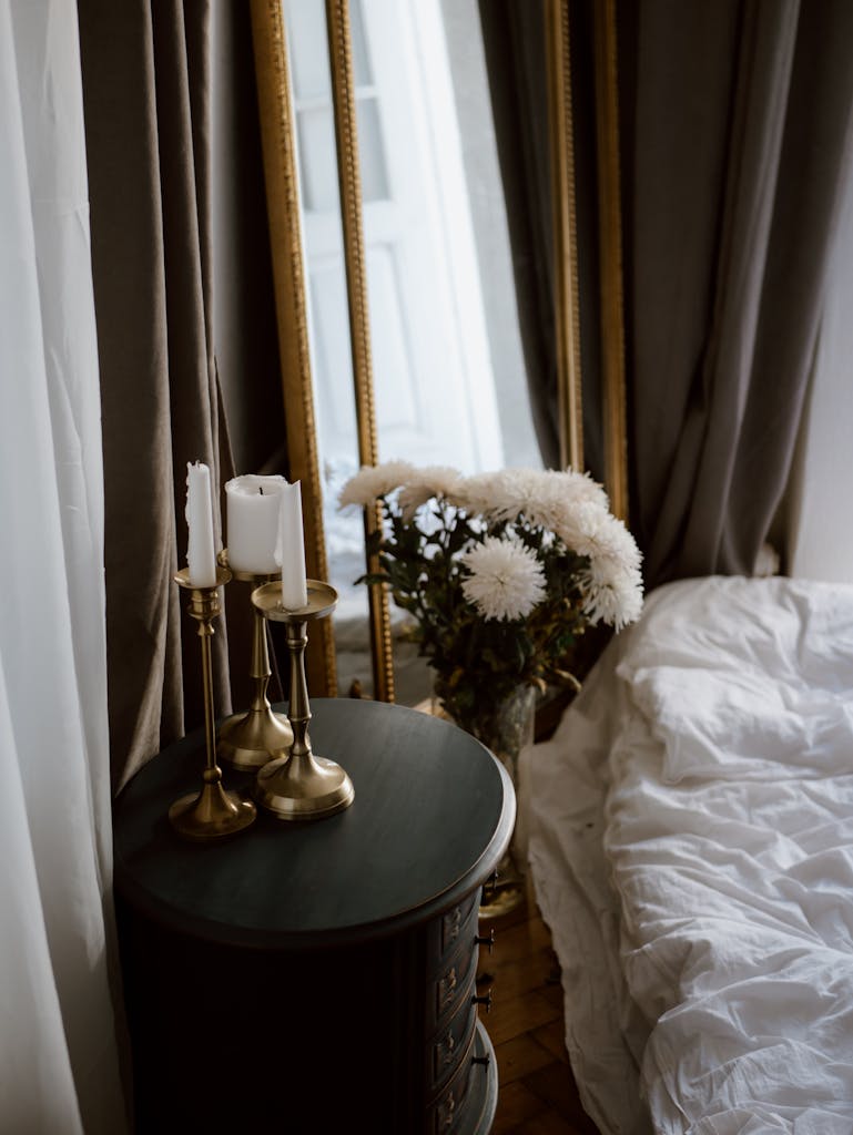 Cozy bedroom setup featuring candles, white flowers and a decorative mirror.