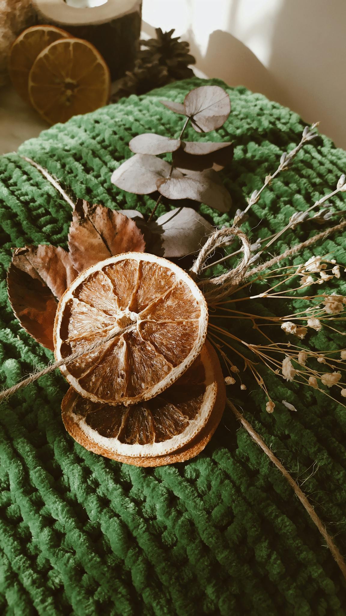 Elegant autumn-themed decoration with dried oranges and leaves on a textured surface.