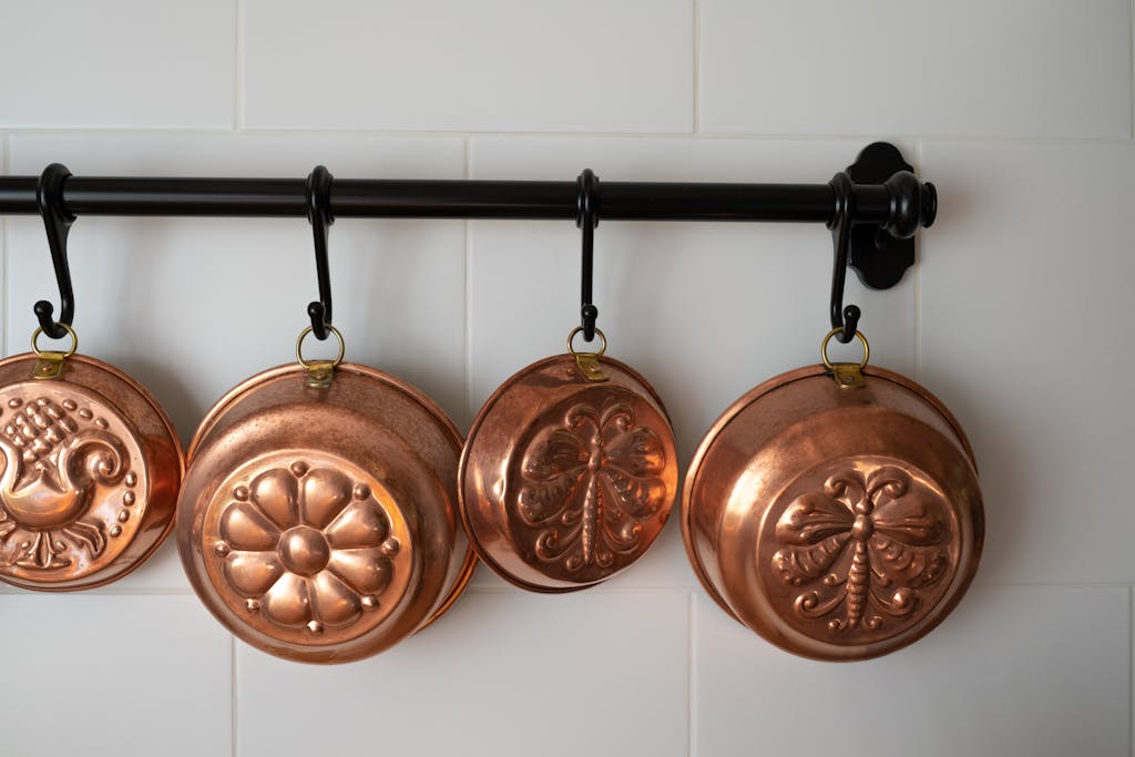 Elegant vintage copper pots hanging in a modern white-tiled kitchen interior, evoking nostalgia and style.