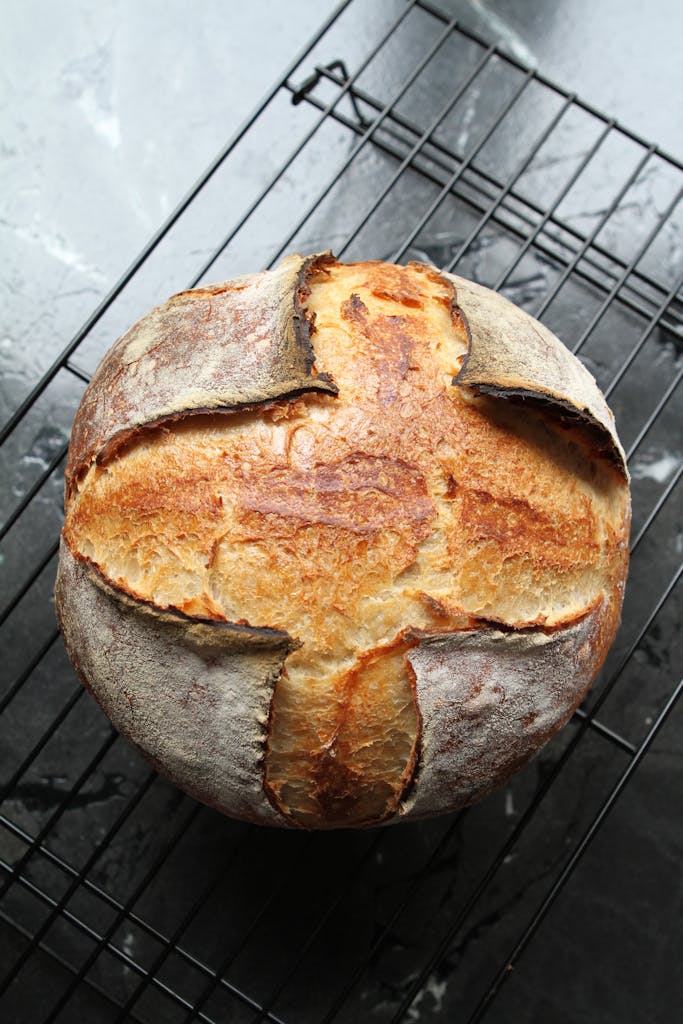 Freshly baked artisan bread with crusty top on cooling rack, top view.