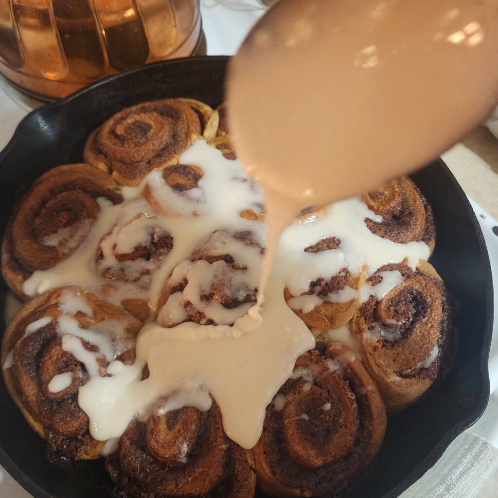 Icing is poured over the Sourdough Discard Cinnamon rolls