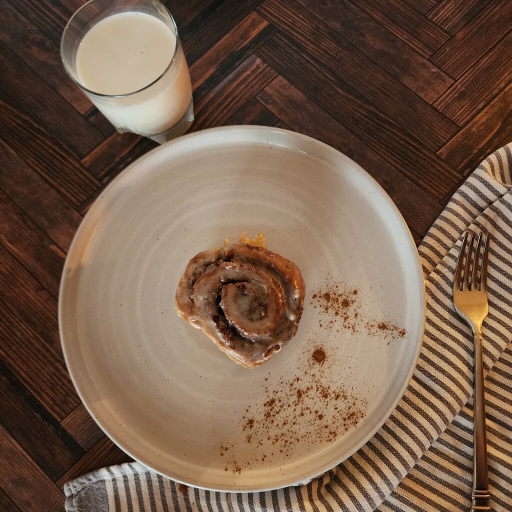 Sourdough Discard Cinnamon roll on a plate with fork and a glass of milk