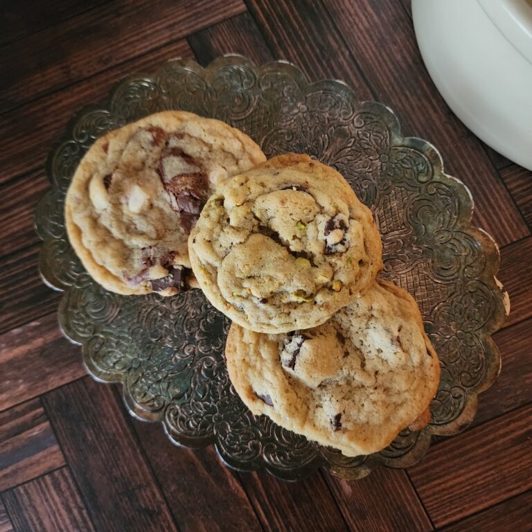 Three delicious chocolate chip cookies rest on an antique silver trivet