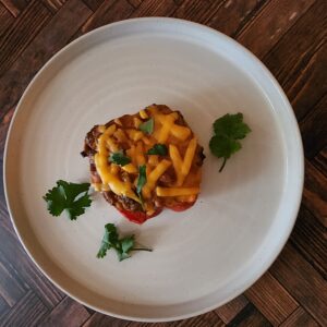 The Best Taco Stuffed Pepper topped with cheese and cilantro on a white plate.