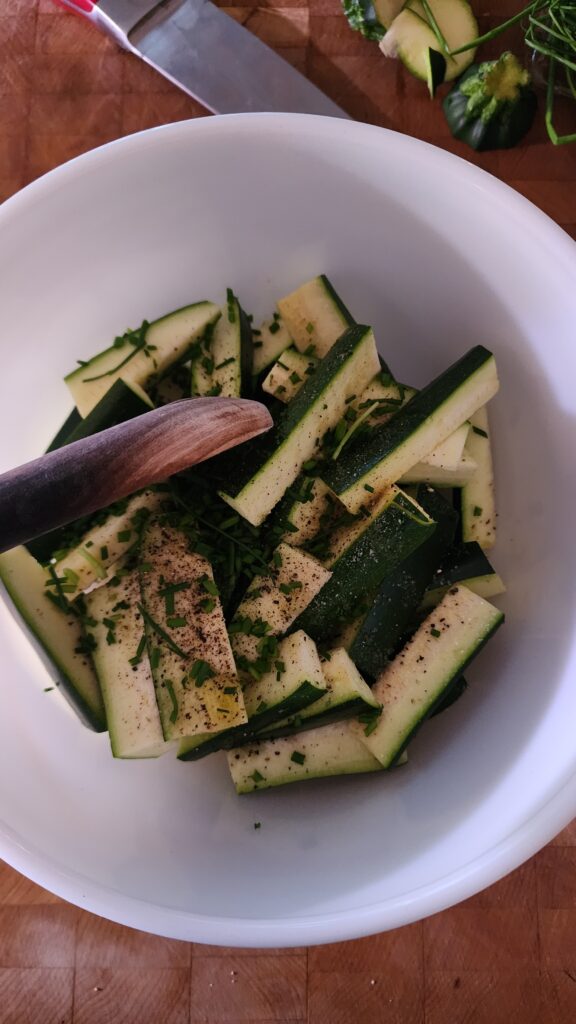 The Perfect Zucchini Side Dish in a bowl with spices and olive oil