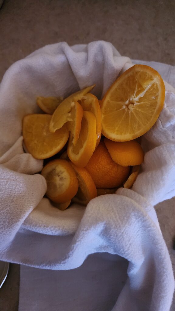 Orange peels sit in a tea towel lined bowl.