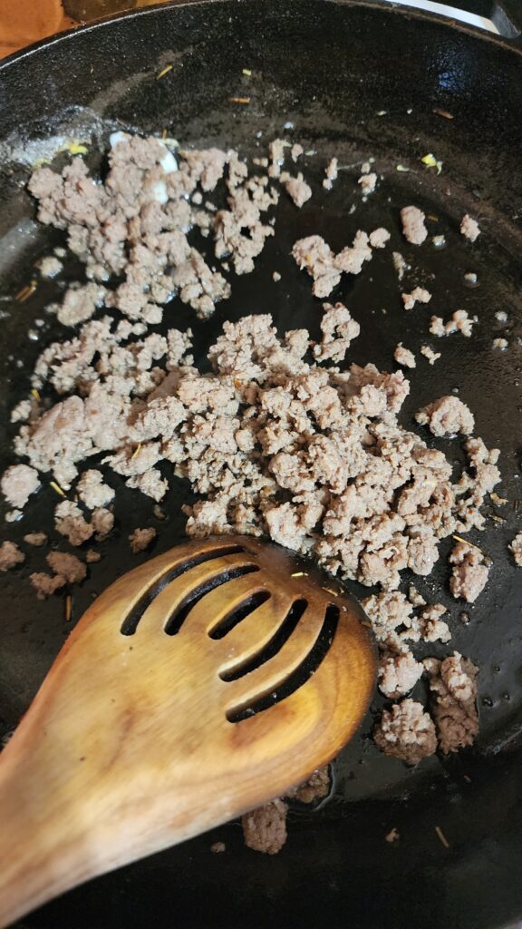 Ground Turkey Sausage is browned in a cast iron skillet