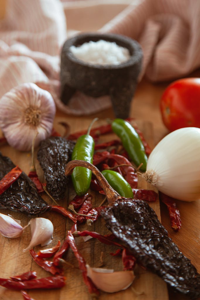 Vibrant Mexican ingredients including chili peppers, garlic, and onion ready for cooking.