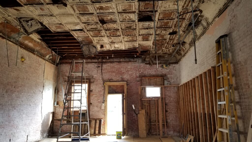 Room with exposed brick walls and an incomplete antique tin ceiling