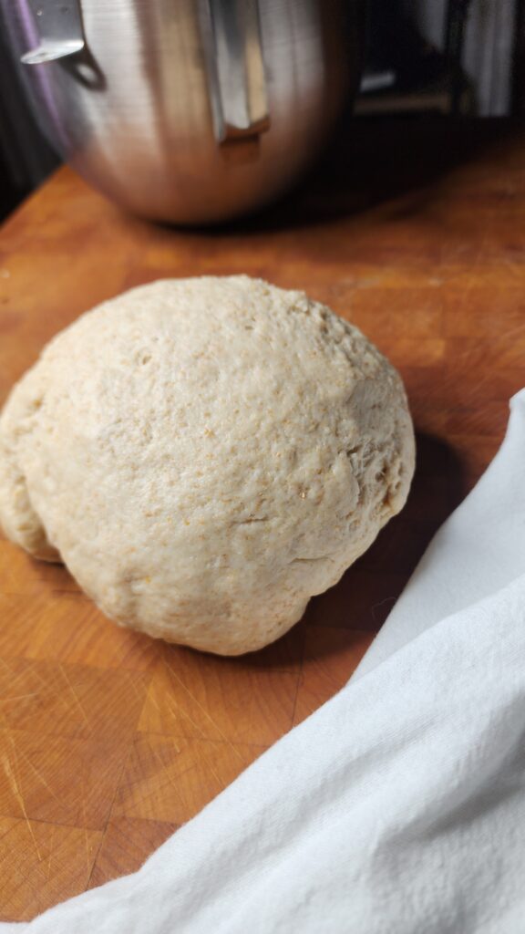 Sourdough Discard tortilla dough resting in a ball on a butcher block