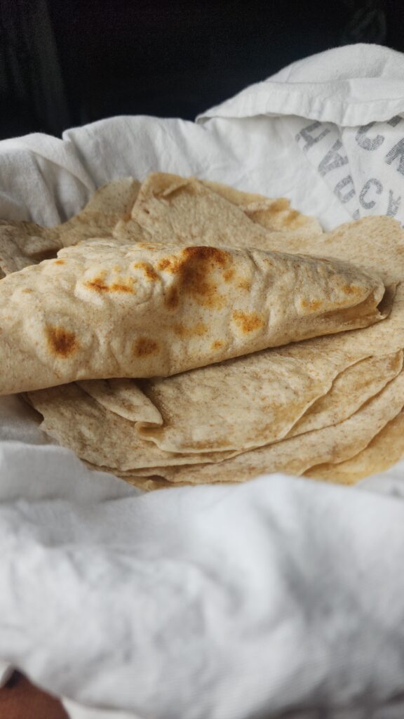 Homemade sourdough tortillas in a bowl with a tea tkwel