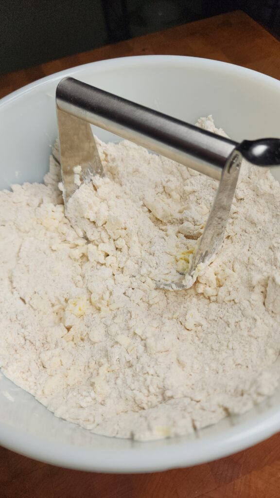 Cold butter is cut into the dry ingredients using a pastry cutter.