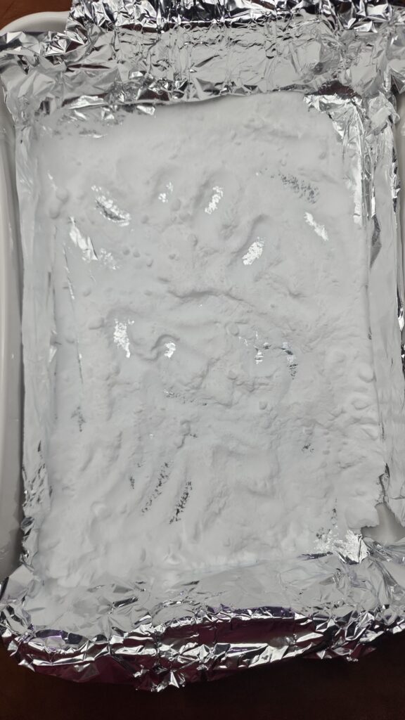 A casserole dish is lined with aluminum foil and baking soda 