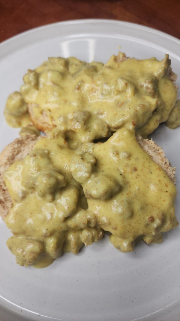 Sourdough Buttermilk Biscuits with Creamy Tumeric Sausage Gravy on a white plate