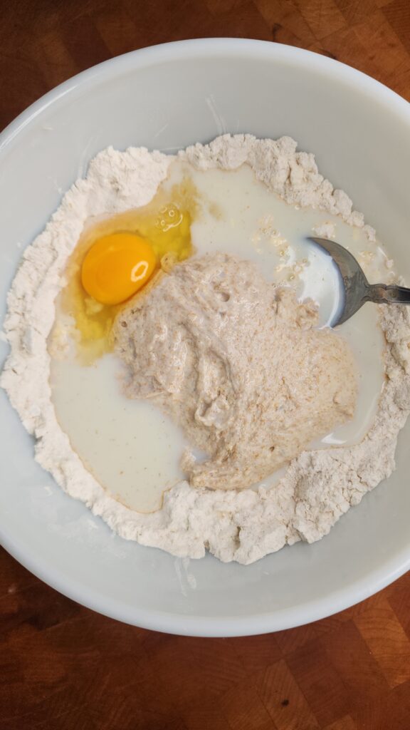 Wet ingredients are added to the dry ingredients in a white mixing bowl 