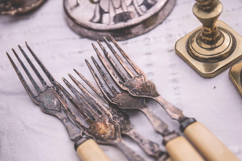 Close-up of elegant vintage silverware set on a classic white tablecloth, showcasing intricate design.