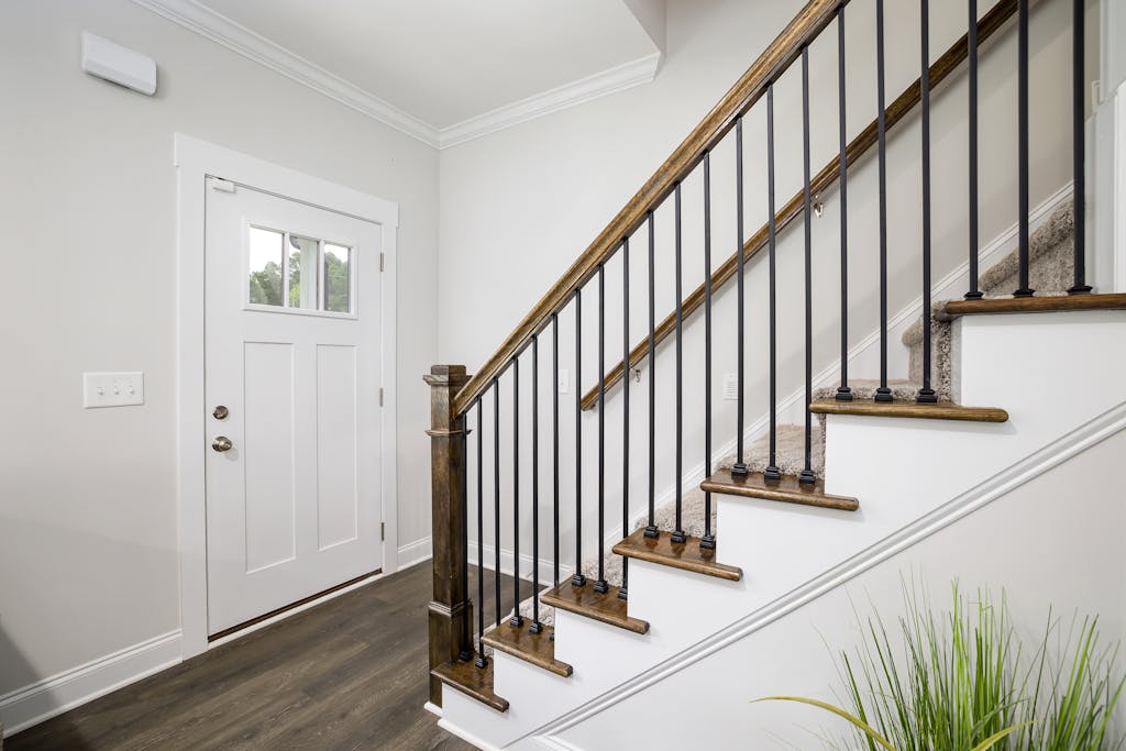 Bright and clean modern stairway with wooden accents and white trim in a minimalist home.