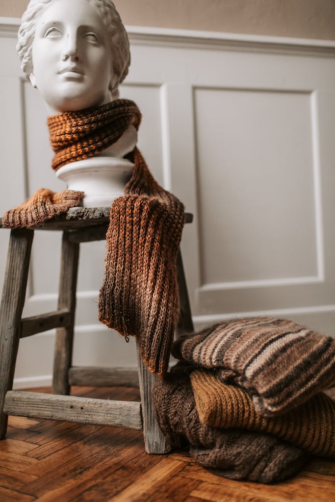Cozy warm knitwear draped over a vintage stool indoors, perfect for winter fashion.