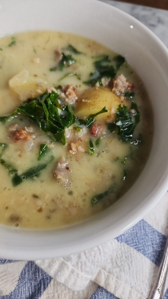 A warm bowl of zuppa tuscana on a tea towel is ready to be enjoyed as a cozy fall meal.