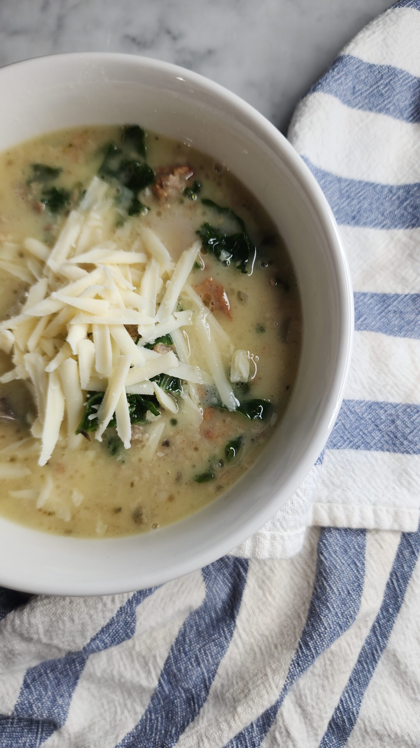 A cozy bowl of Zuppa Tuscana is garnished with grated parmesan cheese showcasing a comforting meal for chilly evenings.