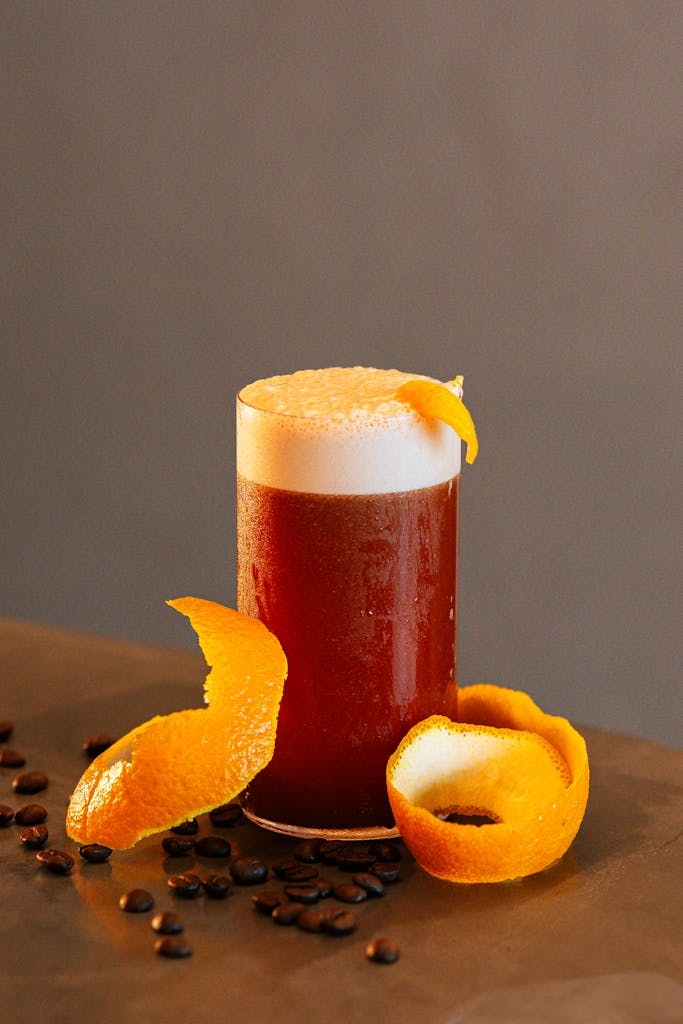 A stylish coffee cocktail served in a glass with a vibrant orange peel garnish.