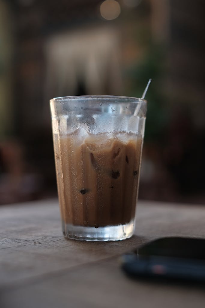 Chilled glass of iced coffee on a table with a straw, ideal for a cool refreshment.