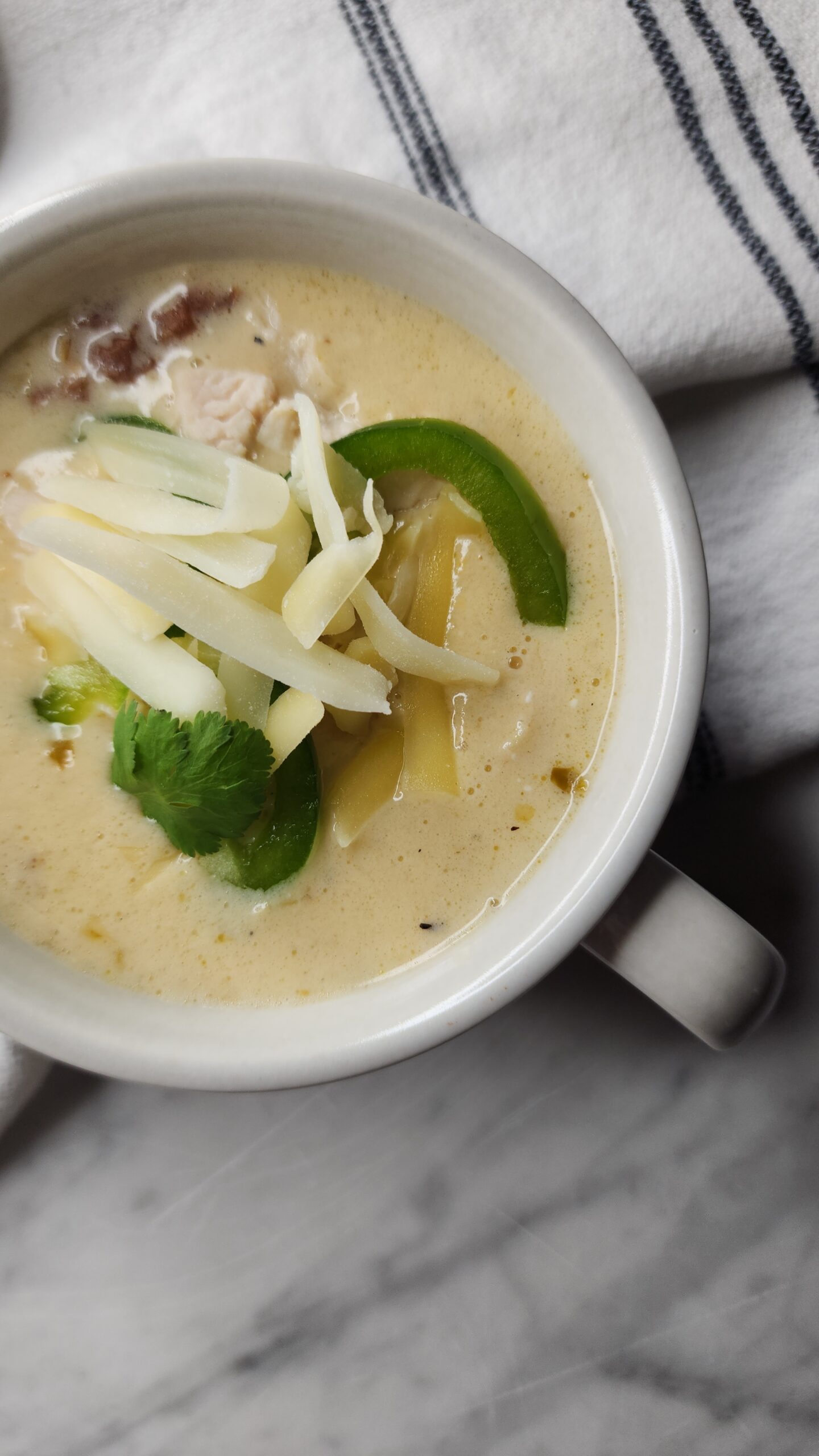 A hearty bowl of keto chicken enchilada soup on a marble surface