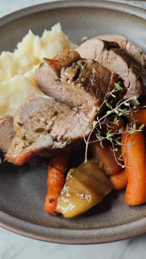 Juicy Maple Apple Pork Tenderloin on a plate with carrots, tender apples, and creamy mashed potatoes. 