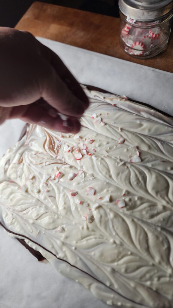 Crushed peppermint candies are sprinkled over layers of chocolate to make festive holiday peppermint bark.