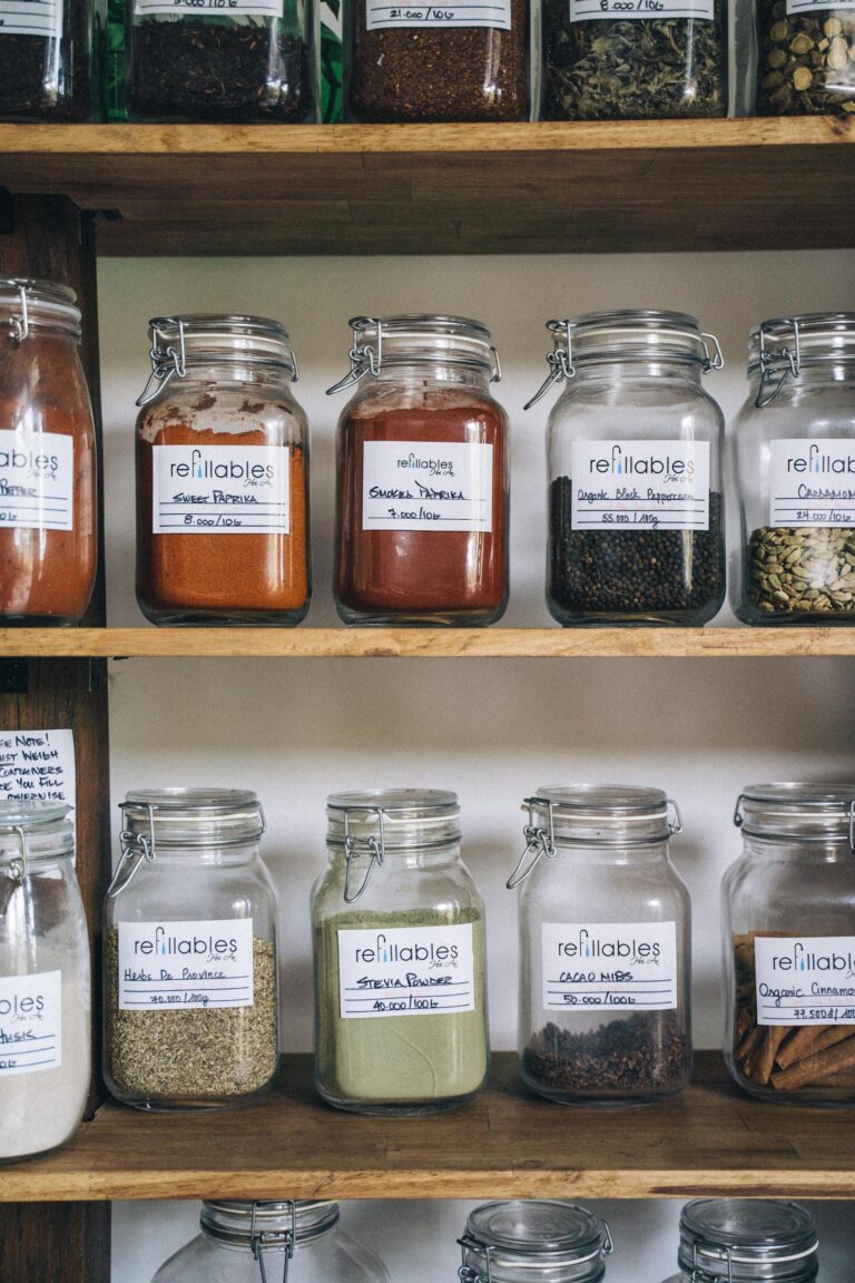 Organized eco-friendly glass jars filled with various spices on a wooden shelf for sustainable food storage.