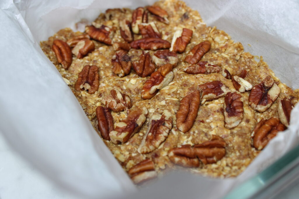 Healthy pecan date bars pressed into a square dish. 