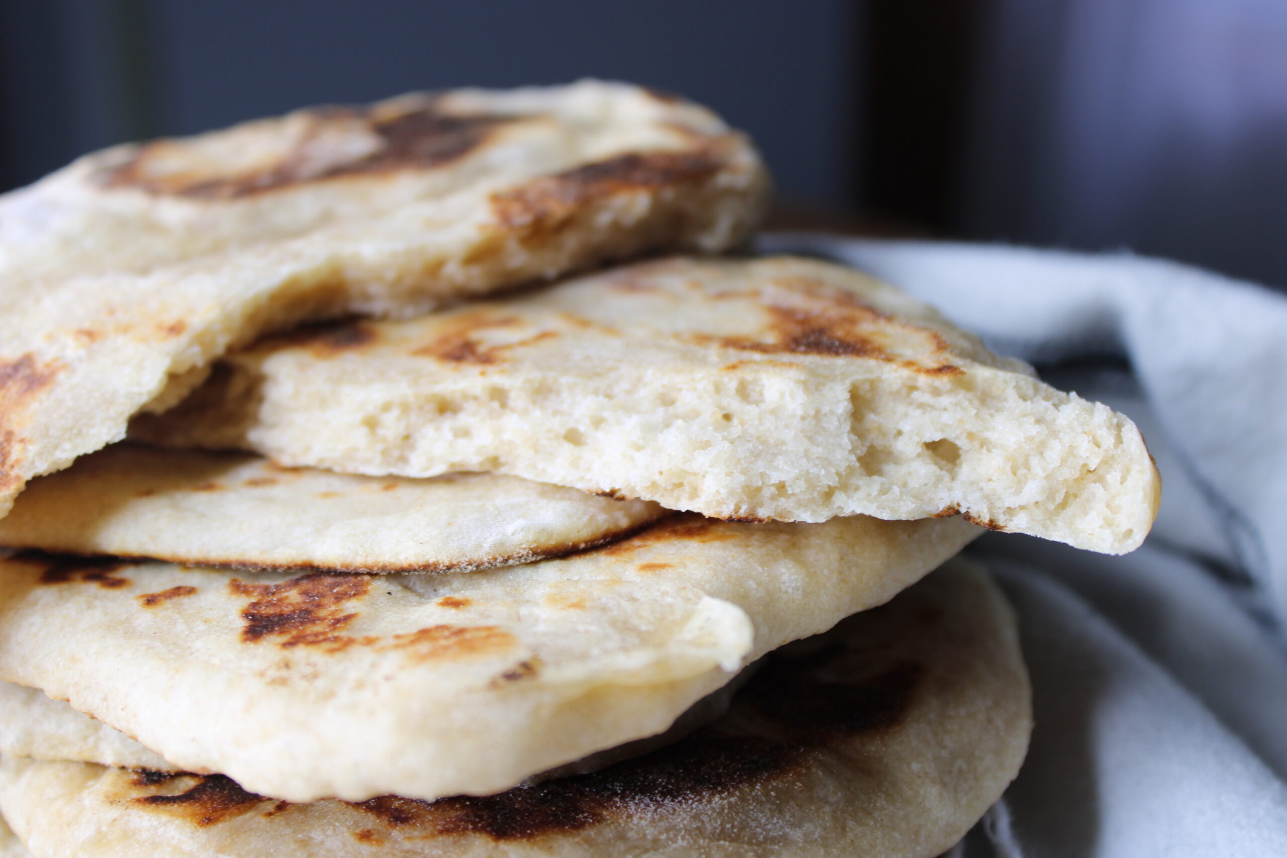 A warm stack of homemade sourdough naan bread ready to eat for a cozy side dish.