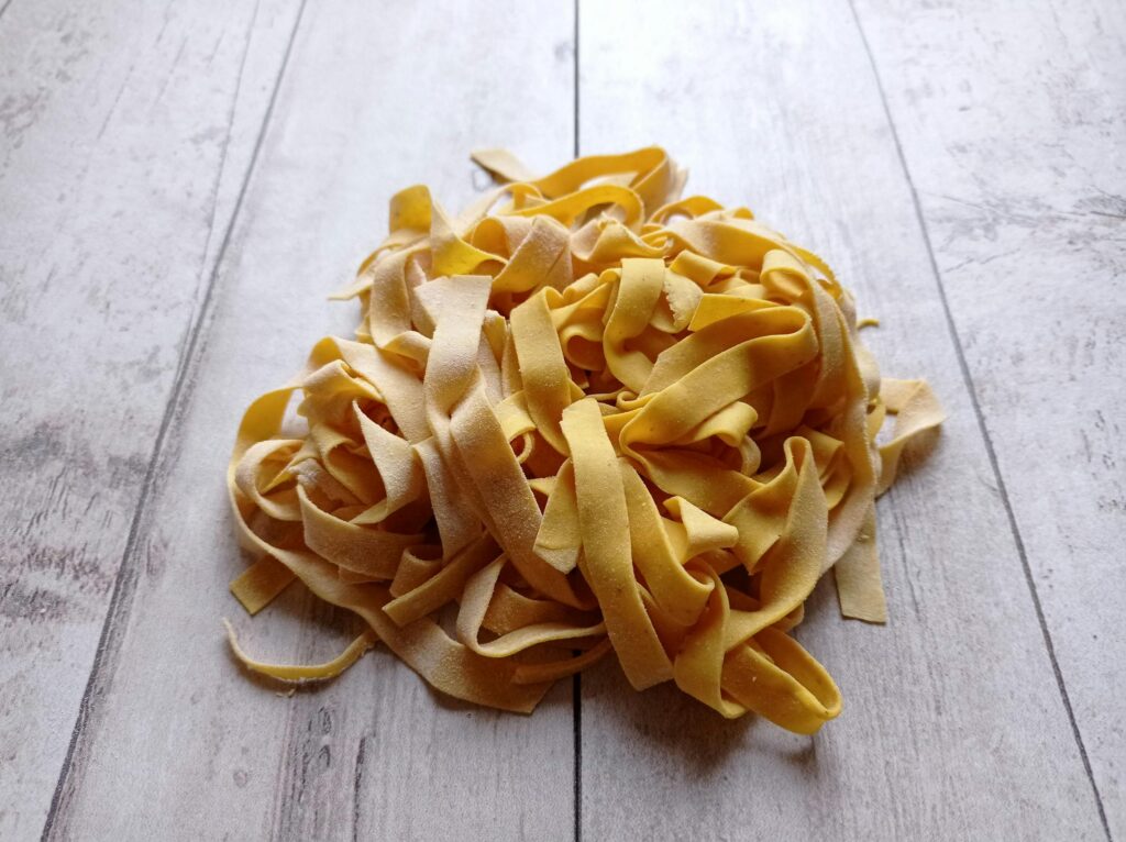 Close-up of homemade tagliatelle on a wooden surface, perfect for Italian cuisine concepts.
