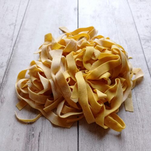 Close-up of homemade tagliatelle on a wooden surface, perfect for Italian cuisine concepts.