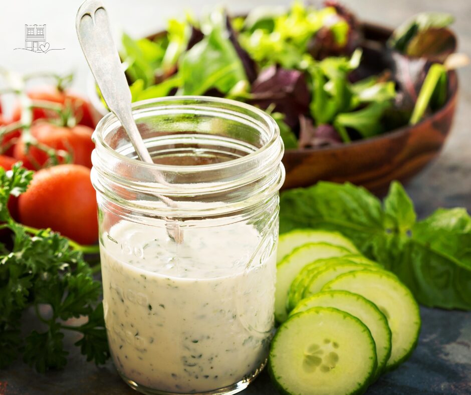Homemade probiotic ranch dressing in a mason jar surrounded by fresh vegetables.