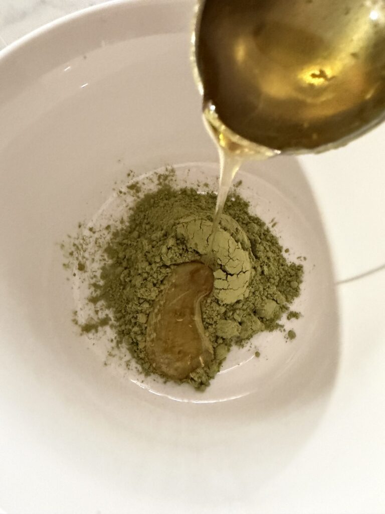 Honey and matcha green tea powder are mixed to make a paste.