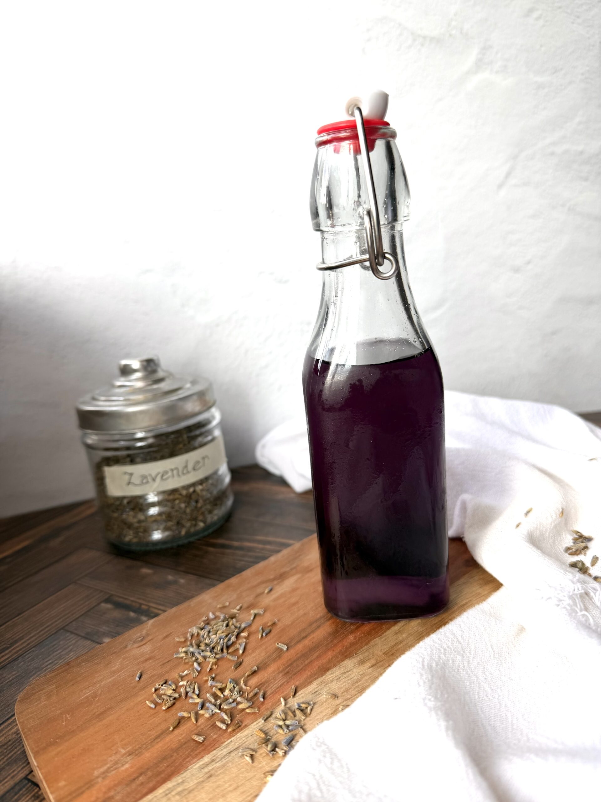 A bottle of lavender simple syrup on a wooden surface.