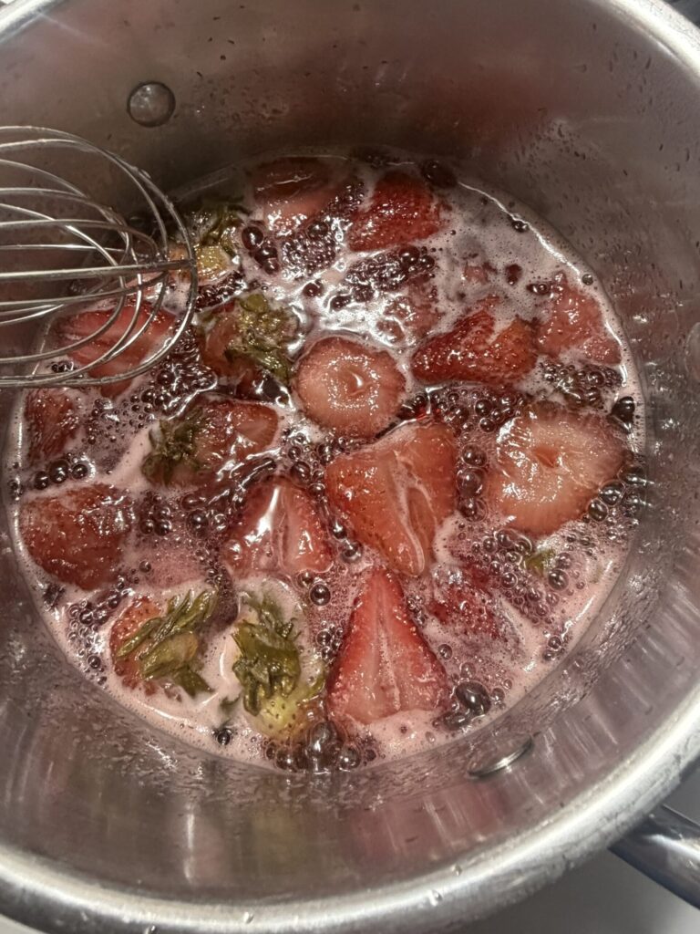 Fresh strawberries, sugar, and water are being boiled to create a strawberry simple syrup. 