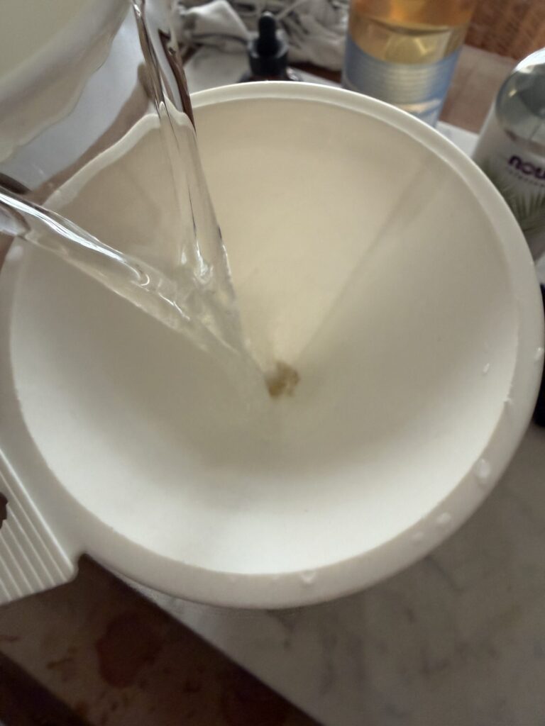 Water is being poured through a funnel into a glass spray bottle.
