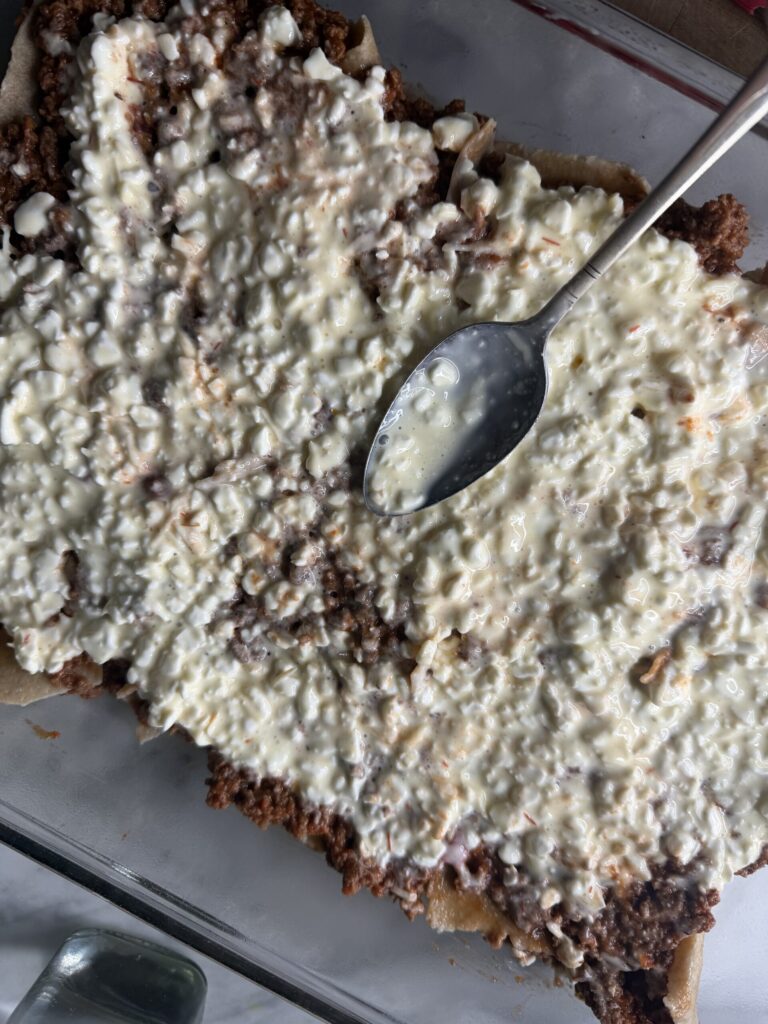 Cottage cheese mixture is spread over a meat sauce layer in homemade lasagna. 