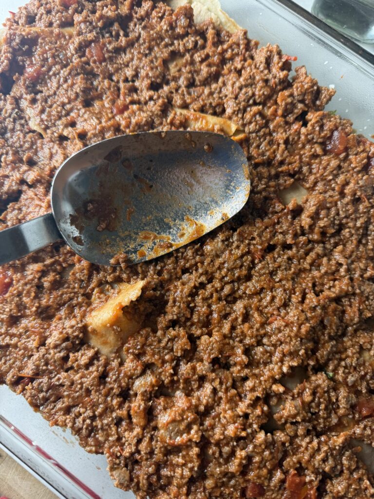 Meat sauce is spread in a layer to make homemade lasagna. 