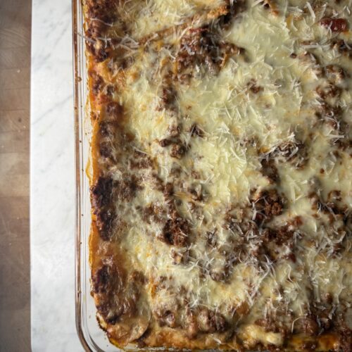 Fresh out of the oven bubbly homemade sourdough lasagna on a marble surface.