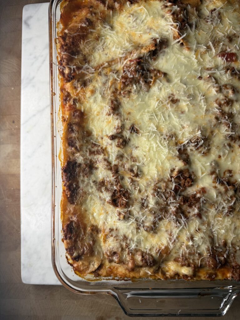 Fresh out of the oven bubbly homemade sourdough lasagna on a marble surface.